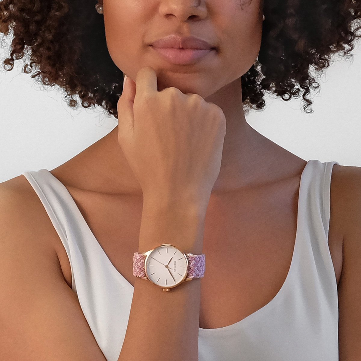 Montre Tweed Co. modèle Rose avec boîtier or rose et bracelet tressé rose et blanc, élégamment posée.
